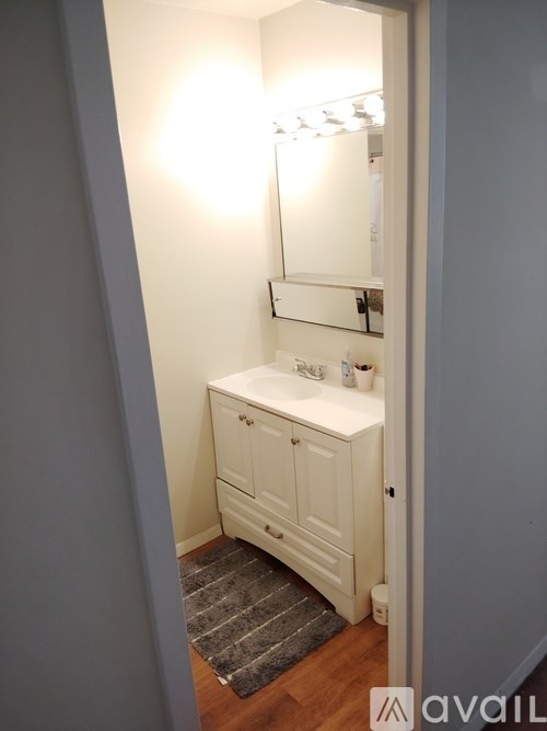 A bathroom with a white cabinet and a mirror above it.