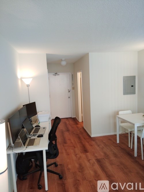 A room with a desk, laptop, chair, and a lamp.