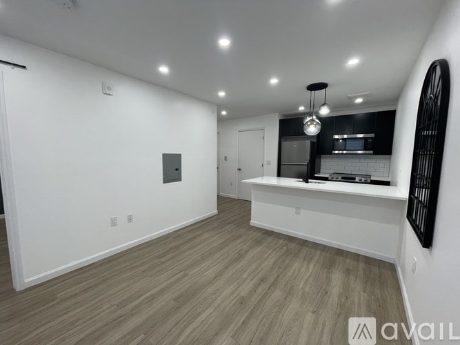 A spacious room with wooden flooring and a large mirror on the wall.