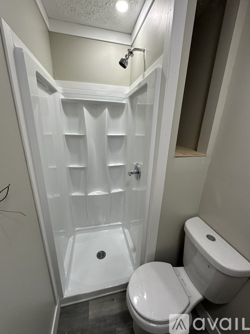A white toilet and shower stall in a bathroom.
