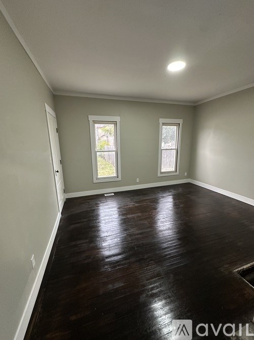 A room with wooden floors and two windows.