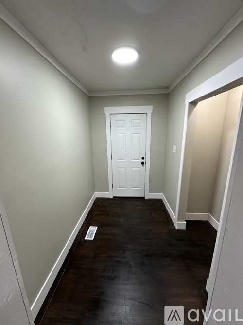 A hallway with a white door and wooden floor.