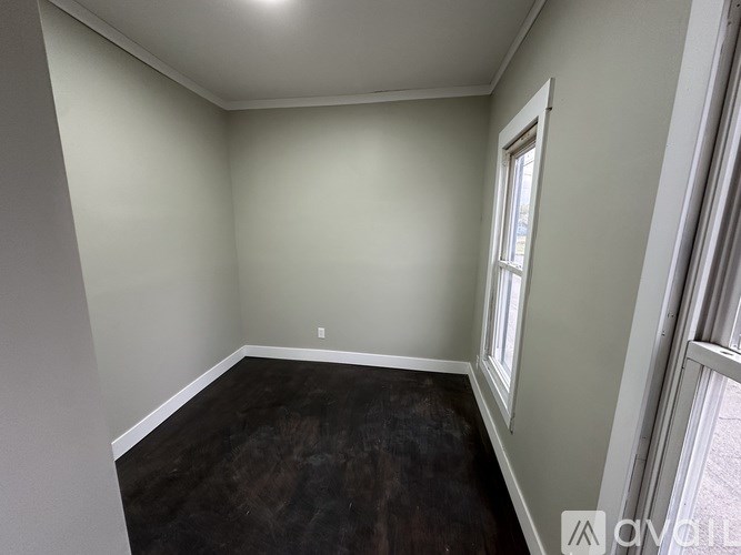 A room with a window and a wooden floor.
