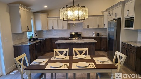 A kitchen with a table set for four with a chandelier hanging above.