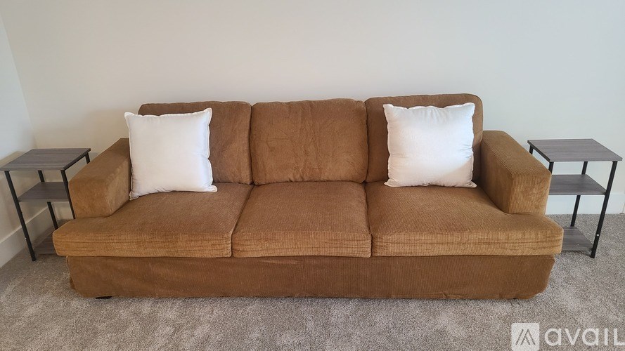 A brown couch with two white pillows sits in a room.