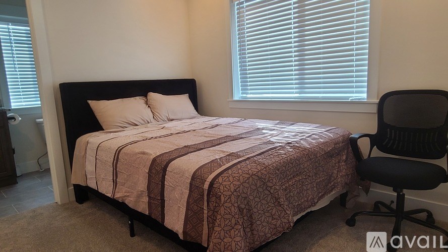 A bedroom with a bed, chair, and window with blinds.