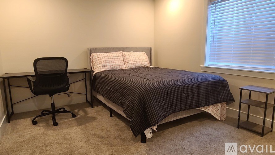A bedroom with a bed, chair, and window.