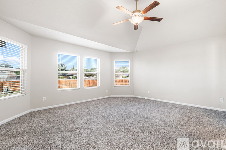 A room with a ceiling fan and three windows.