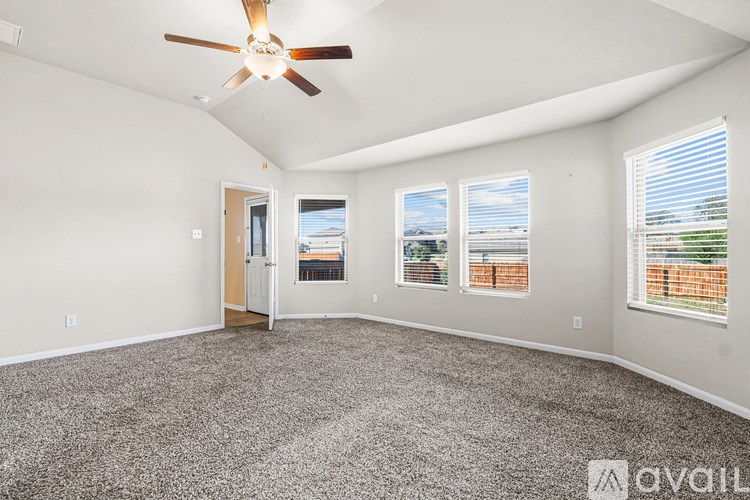A spacious room with a ceiling fan and large windows.