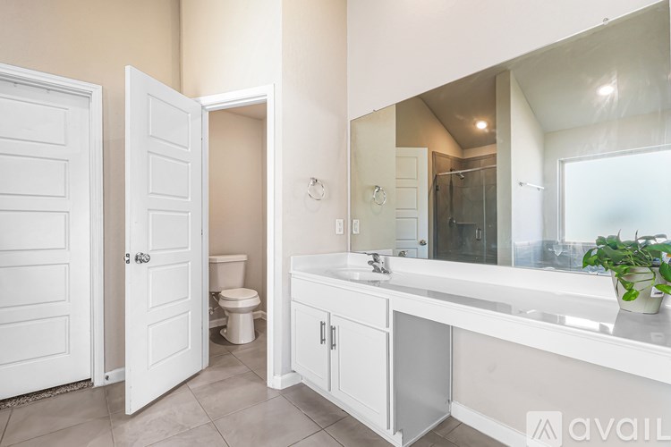 A bathroom with a toilet, sink, and mirror.