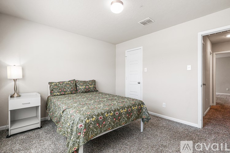 A bedroom with a bed, nightstand, and lamp.