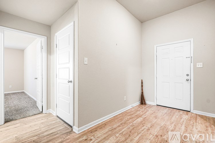 A room with three doors and a broom leaning against one wall.