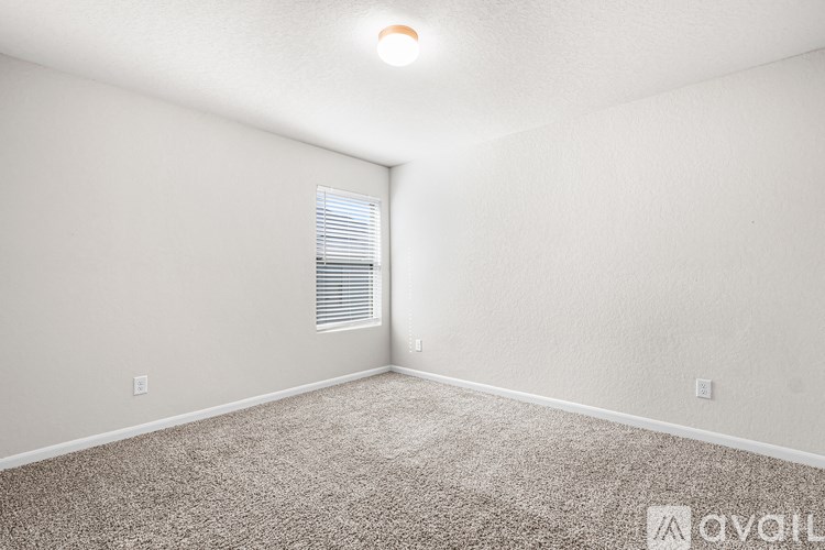 A room with a carpeted floor and a window with blinds.
