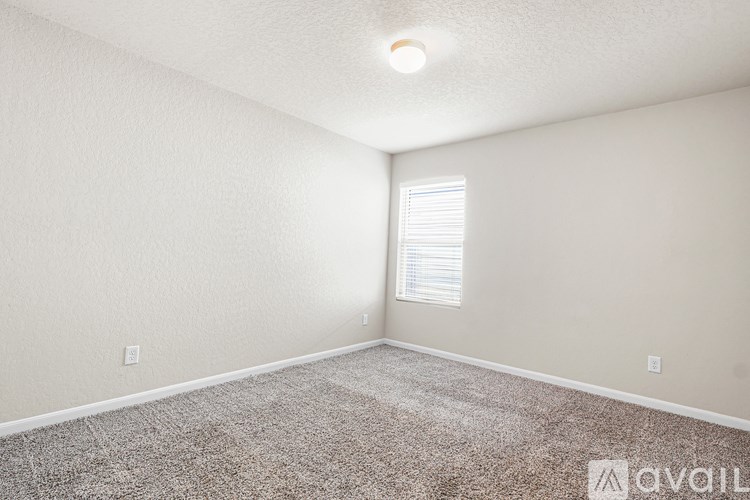 A room with a carpeted floor and a window with blinds.