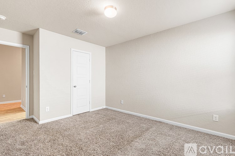A room with a white door and carpeted floor.