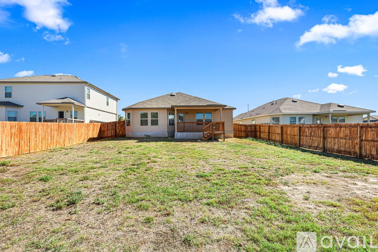 A backyard with a wooden fence and two houses.