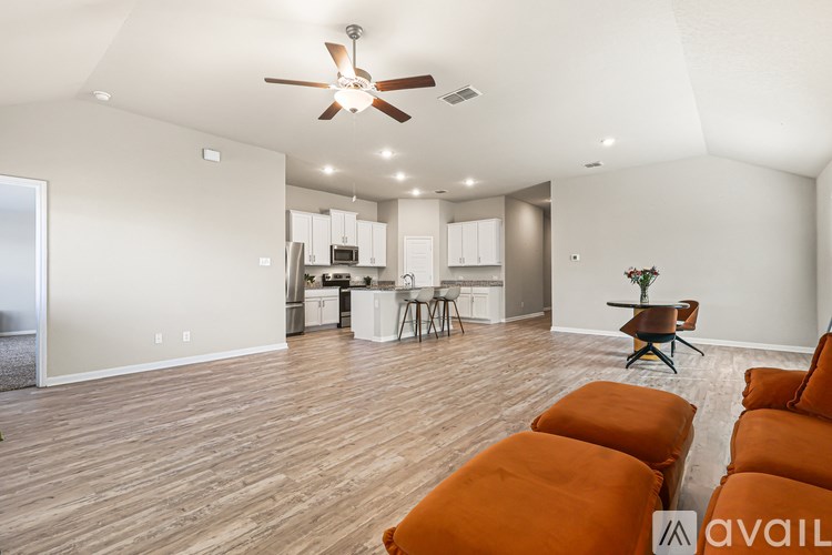 A living room with a ceiling fan and orange ottomans.