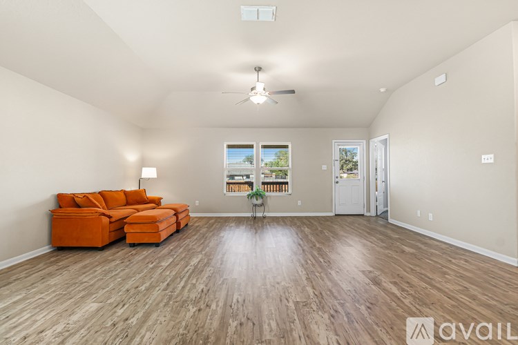 A living room with a large orange sofa and a wooden floor.