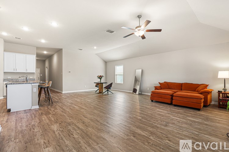 A living room with a brown sofa and a white kitchen in the background.