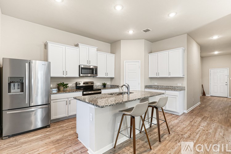 A kitchen with a stainless steel refrigerator, microwave, and bar stools.