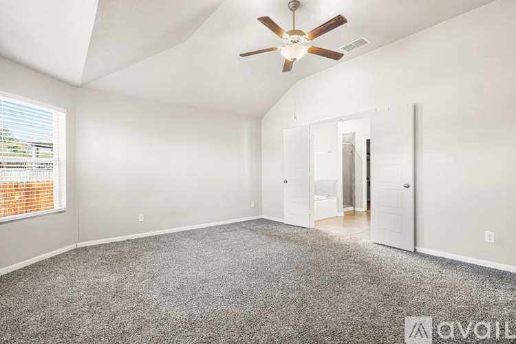 A spacious room with a ceiling fan and carpeted floor.