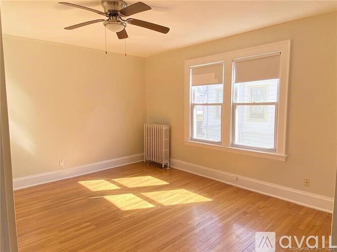 A room with a ceiling fan and a window with a radiator underneath it.