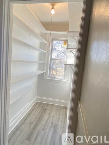 A small, empty room with a window and a wooden floor.