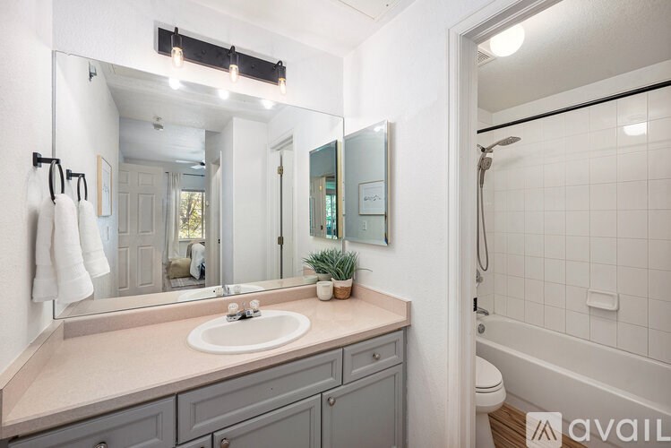 A bathroom with a sink, mirror, and a white towel hanging on the wall.