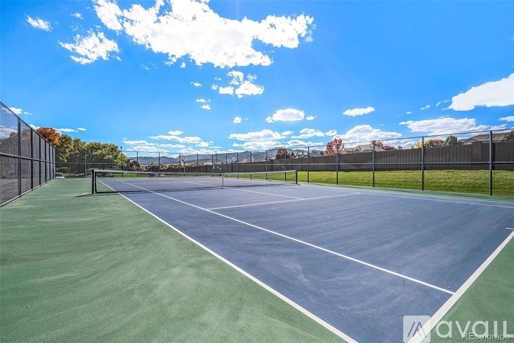 A tennis court with a blue surface and white lines, surrounded by a chain link fence.