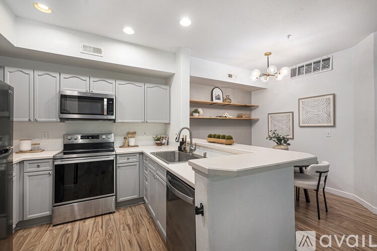 A modern kitchen with stainless steel appliances and wooden flooring.