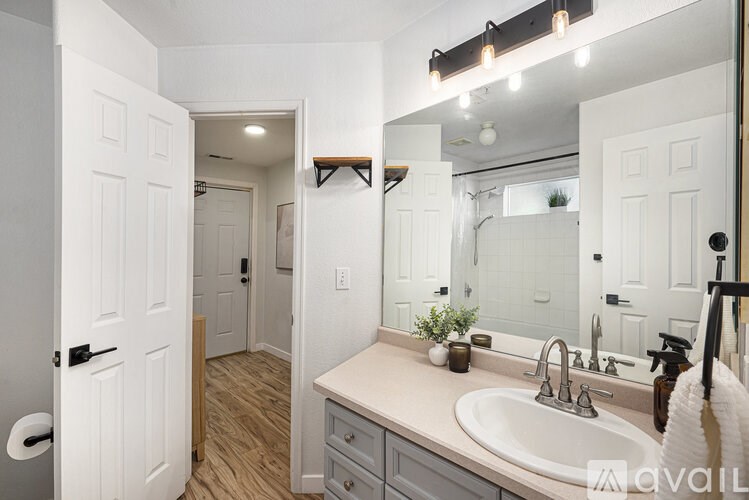 A bathroom with a sink, mirror, and wooden floors.