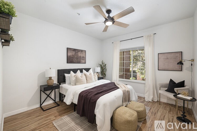 A bedroom with a bed, a chair, and a ceiling fan.