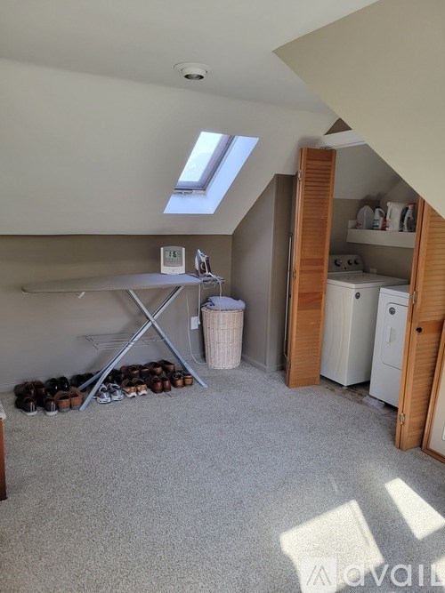 A room with a skylight and a white washing machine.