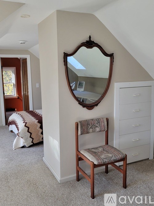A chair sits in a corner of a room with a mirror above it.