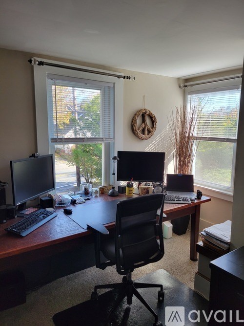A home office with a desk, chairs, and computer monitors.