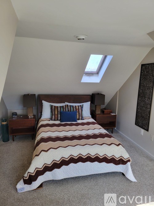 A bedroom with a bed, nightstand, and window.