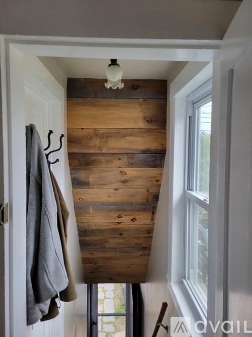 A grey coat hanging on a hook on a white door.