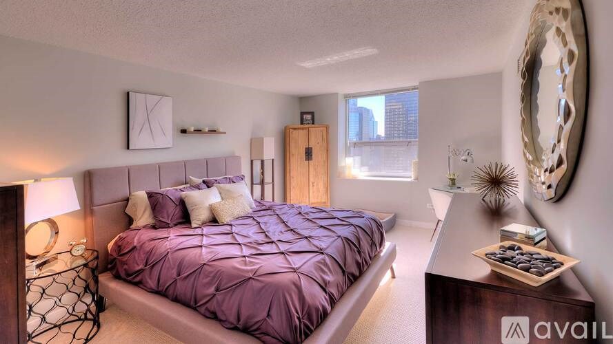 A bedroom with a purple bedspread and a wooden headboard.