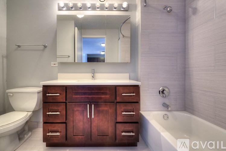 A bathroom with a white countertop and a wooden cabinet.
