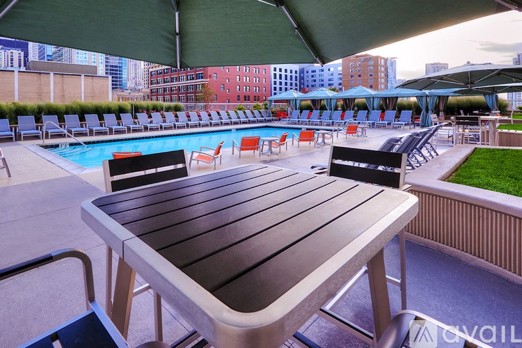 A poolside table is in the foreground of a pool with chairs and umbrellas in the background.