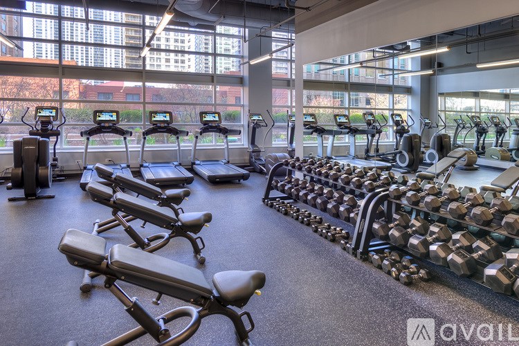 A gym with treadmills, exercise bikes, and dumbbells.