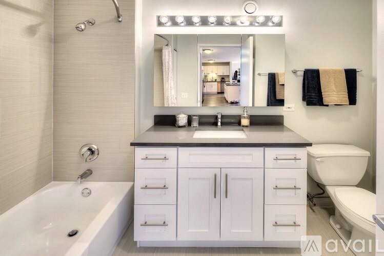 A modern bathroom with a white tub, sink, and toilet.