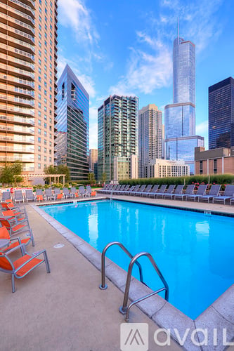 A pool surrounded by chairs and buildings in the background.