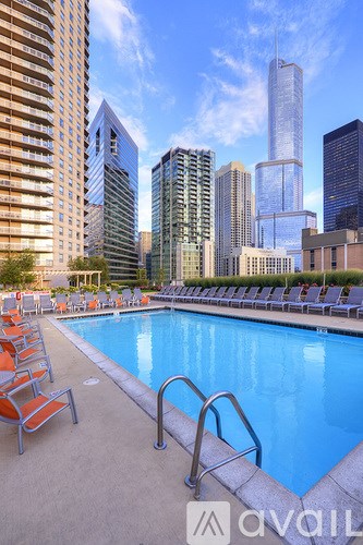 A pool surrounded by chairs and buildings in the background.