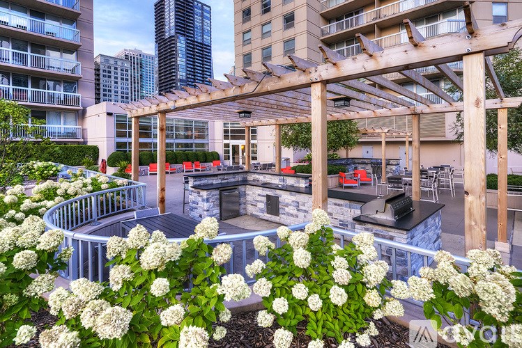 A patio with a fire pit and seating area surrounded by white hydrangeas.