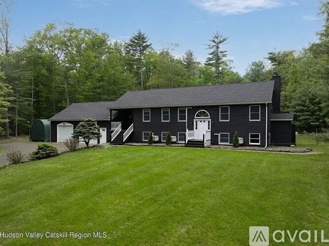 A black house with white trim is for sale in the Hudson Valley Catskill Region.