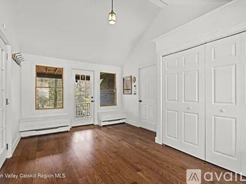A large empty room with wood floors and white walls.
