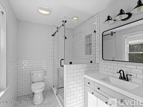A white bathroom with a toilet, sink, and shower.