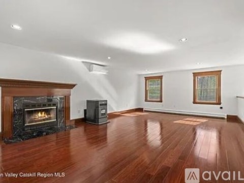 A spacious room with wood flooring and a fireplace.