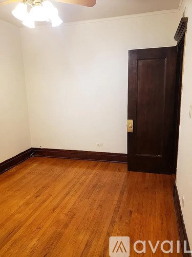 A room with wooden flooring and a brown door.